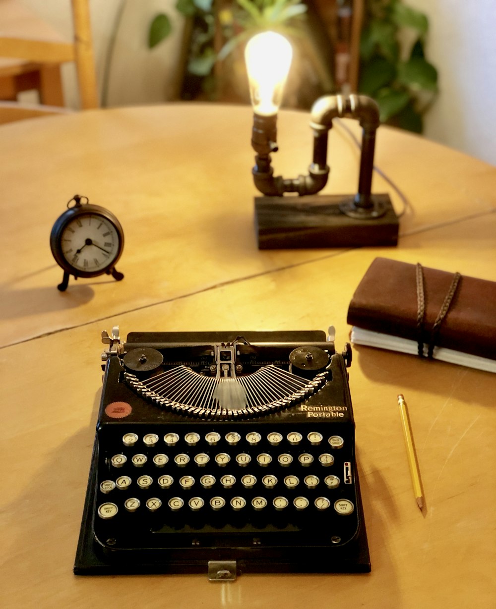 máquina de escribir negra junto al lápiz amarillo, libro marrón, despertador y lámpara de escritorio Steam Punk sobre la mesa