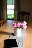 A wooden table adorned with a delicate, patterned table runner.