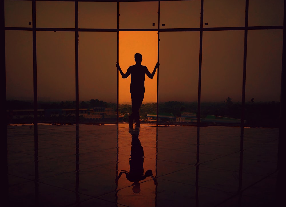 silhouette photography of person standing beside glass walls