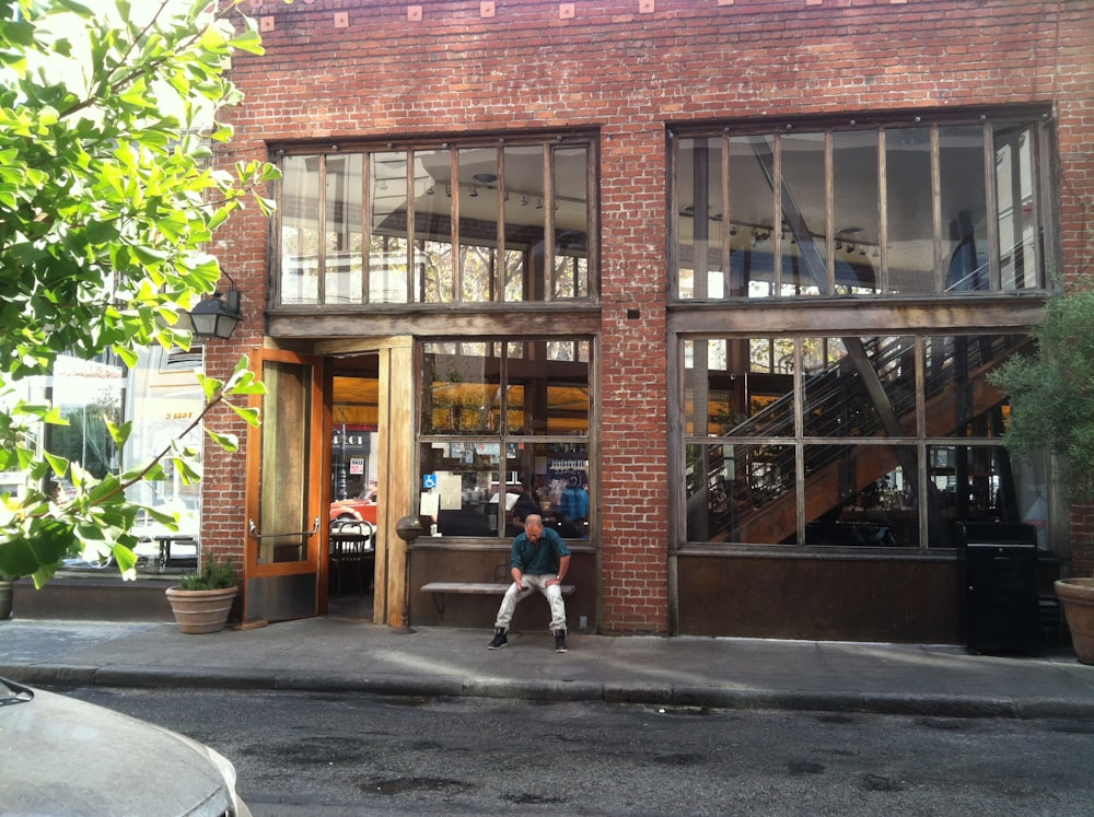 man sitting on bench near brown concrete building