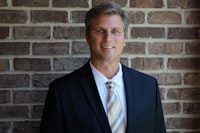 Man in a suit and tie against a brick wall