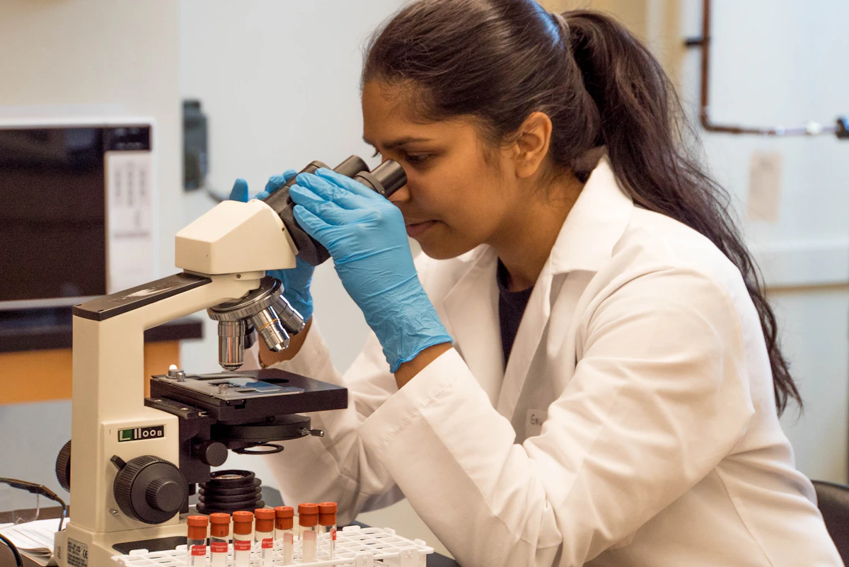 Lab technician examining samples under a microscope