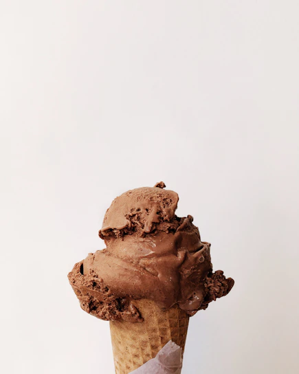 Close-up of a rich chocolate ice cream scoop melting slightly on a waffle cone.