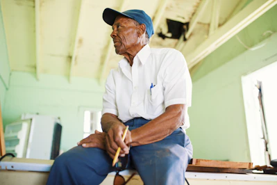 man sitting on slab holding pencil while looking on his right side