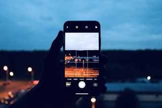 A mentor guiding a person on smartphone photography outdoors with a cityscape background.