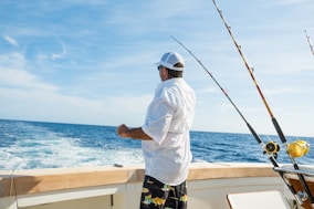 man standing on boat near fishing rods
