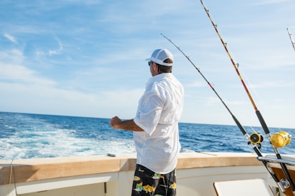 man standing on boat near fishing rods