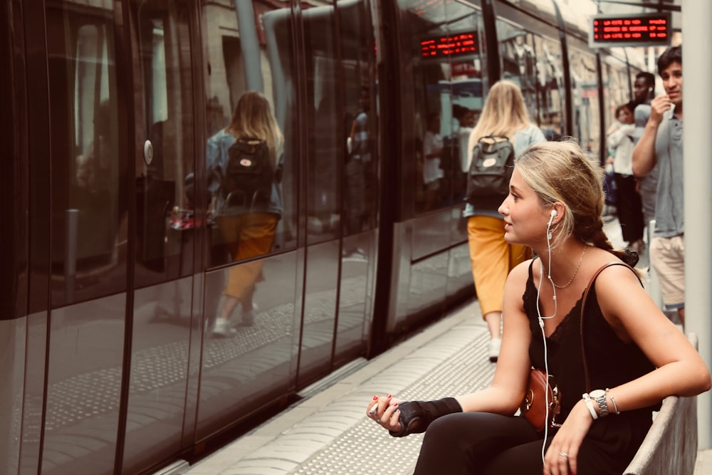 donna che si siede sulla panchina davanti al treno
