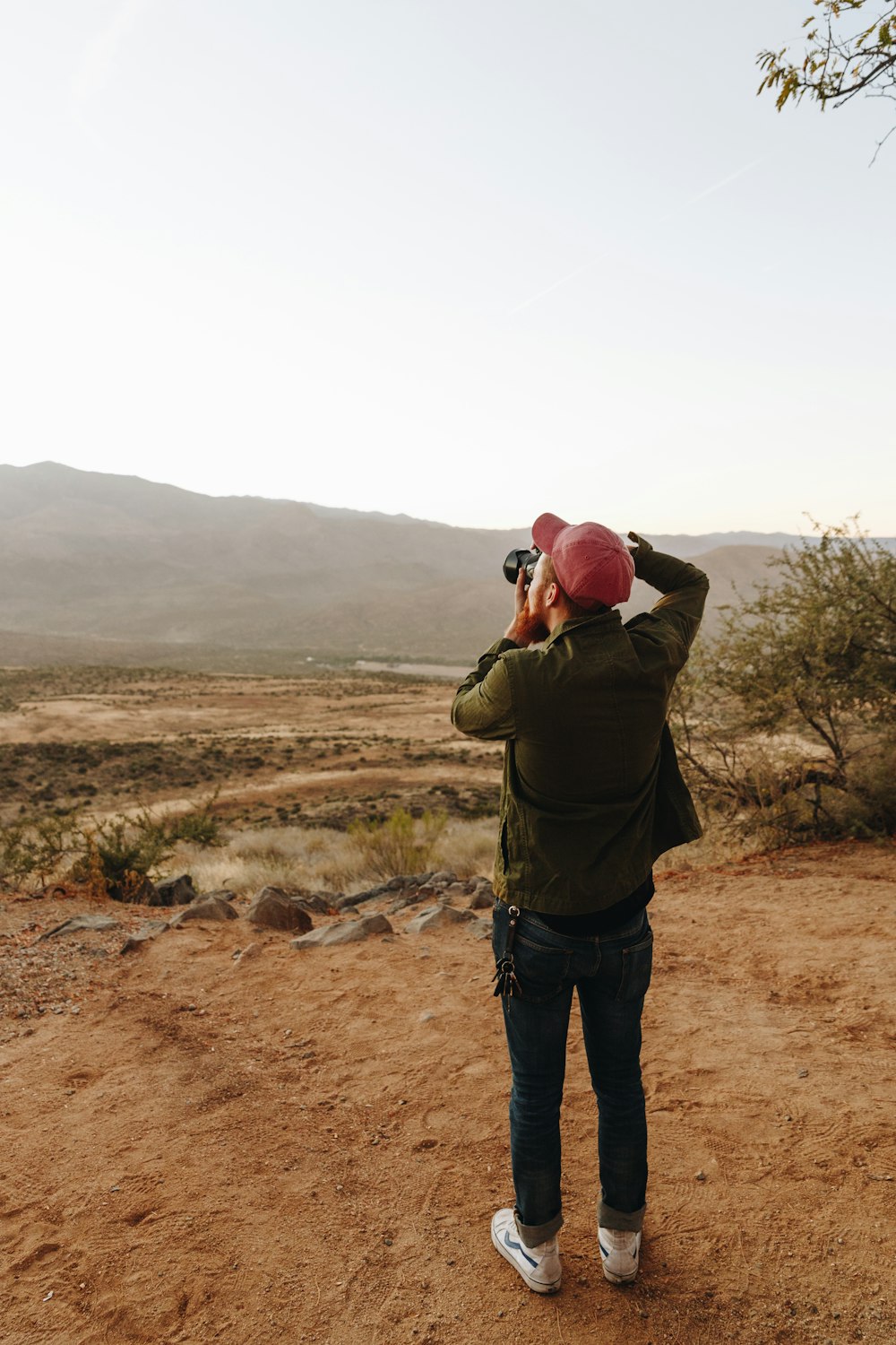 man standing near cliff using DSLR camera