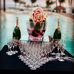 champagne glass and bottle near swimming pool during daytime