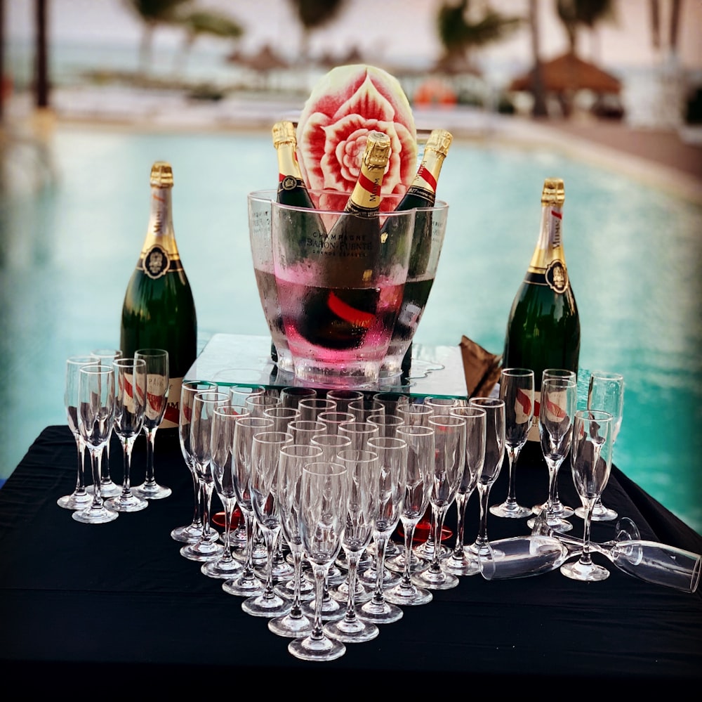 champagne glass and bottle near swimming pool during daytime