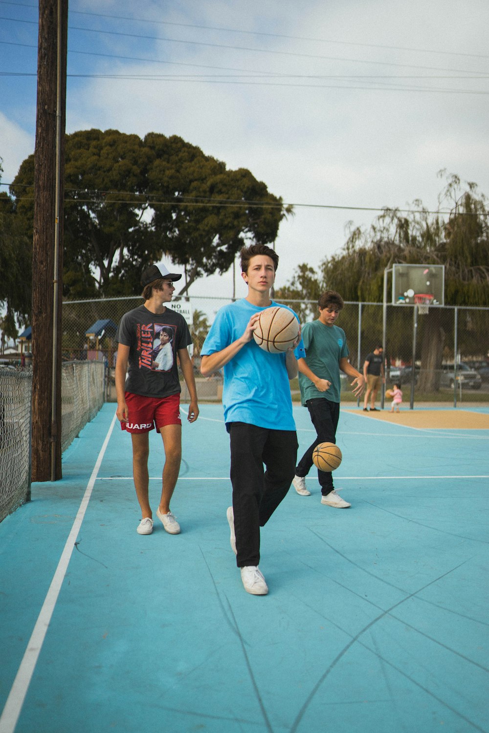 man wearing blue t-shirt and black pants holding basketball during daytime