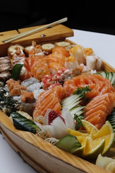 A colorful sushi platter with fresh fish, rice, and garnishes on a wooden table.