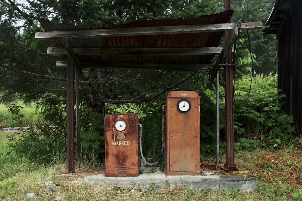 two old rusty gas pumps sitting in a field