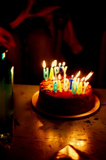 brown icing-covered cake with lighted candles