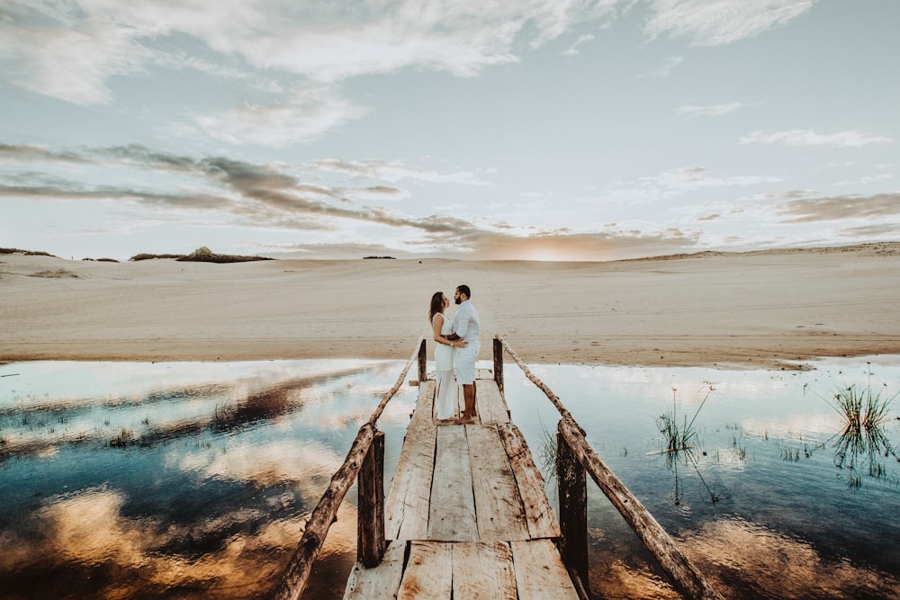 couple face each other on brown wooden dock