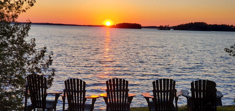 Fünf schwarze Adirondack-Stühle am Strand