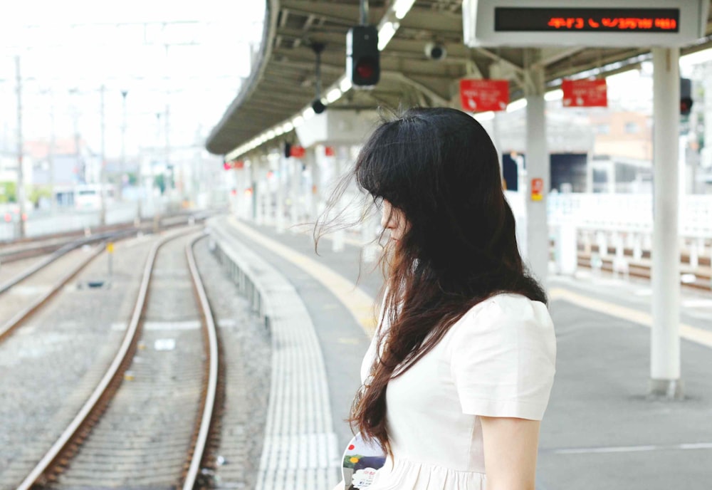 woman wearing white shirt standing beside train railway