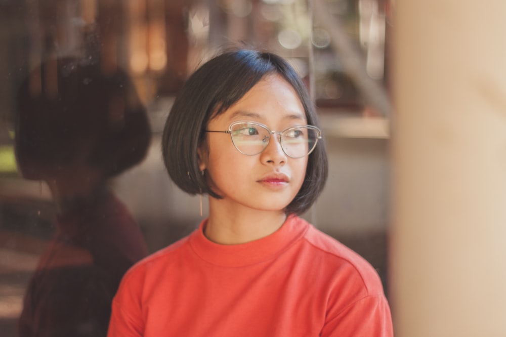 woman wearing red crew-neck shirt and eyeglasses facing her right side