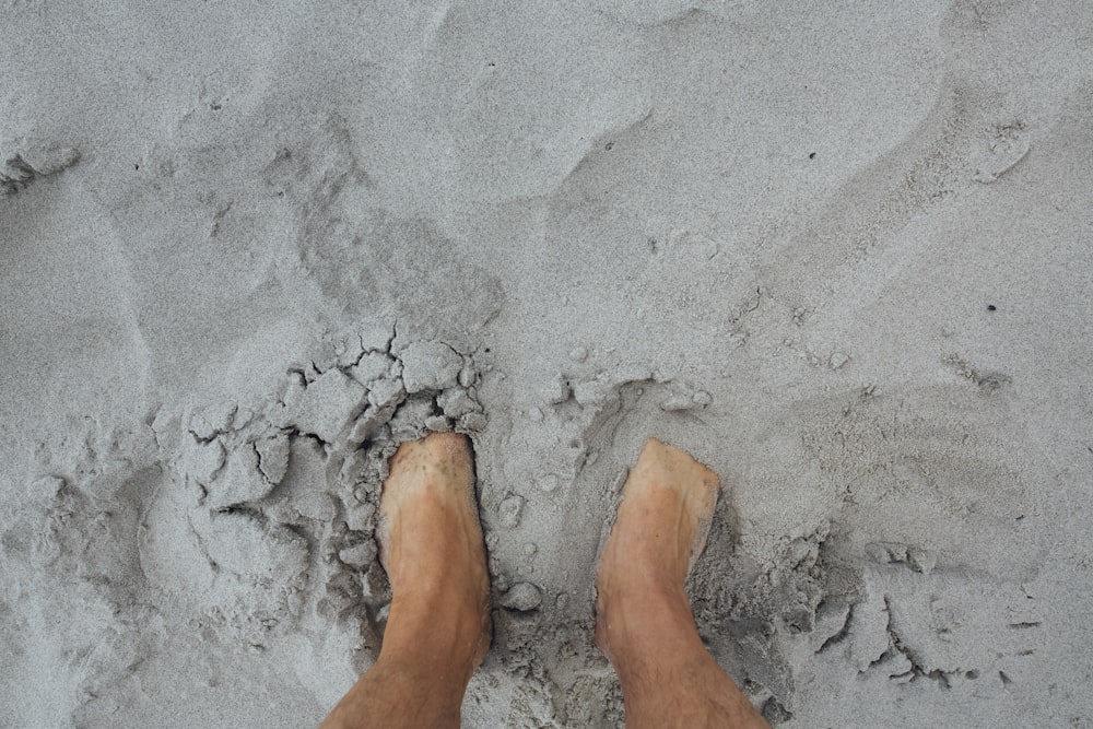 a person standing in the sand with their feet in the sand