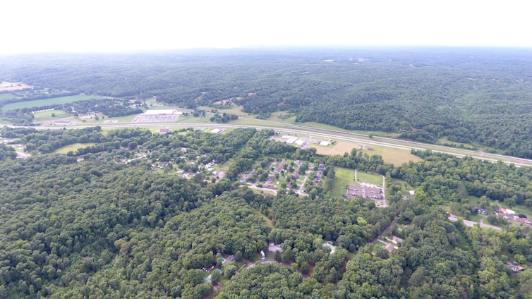 Aerial view of lush green plots near a highway, showcasing open spaces and potential for development.