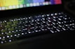 A close-up of a laptop keyboard with glowing backlit keys.