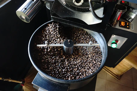 Industrial coffee roaster in action, with rich coffee beans being roasted to perfection.