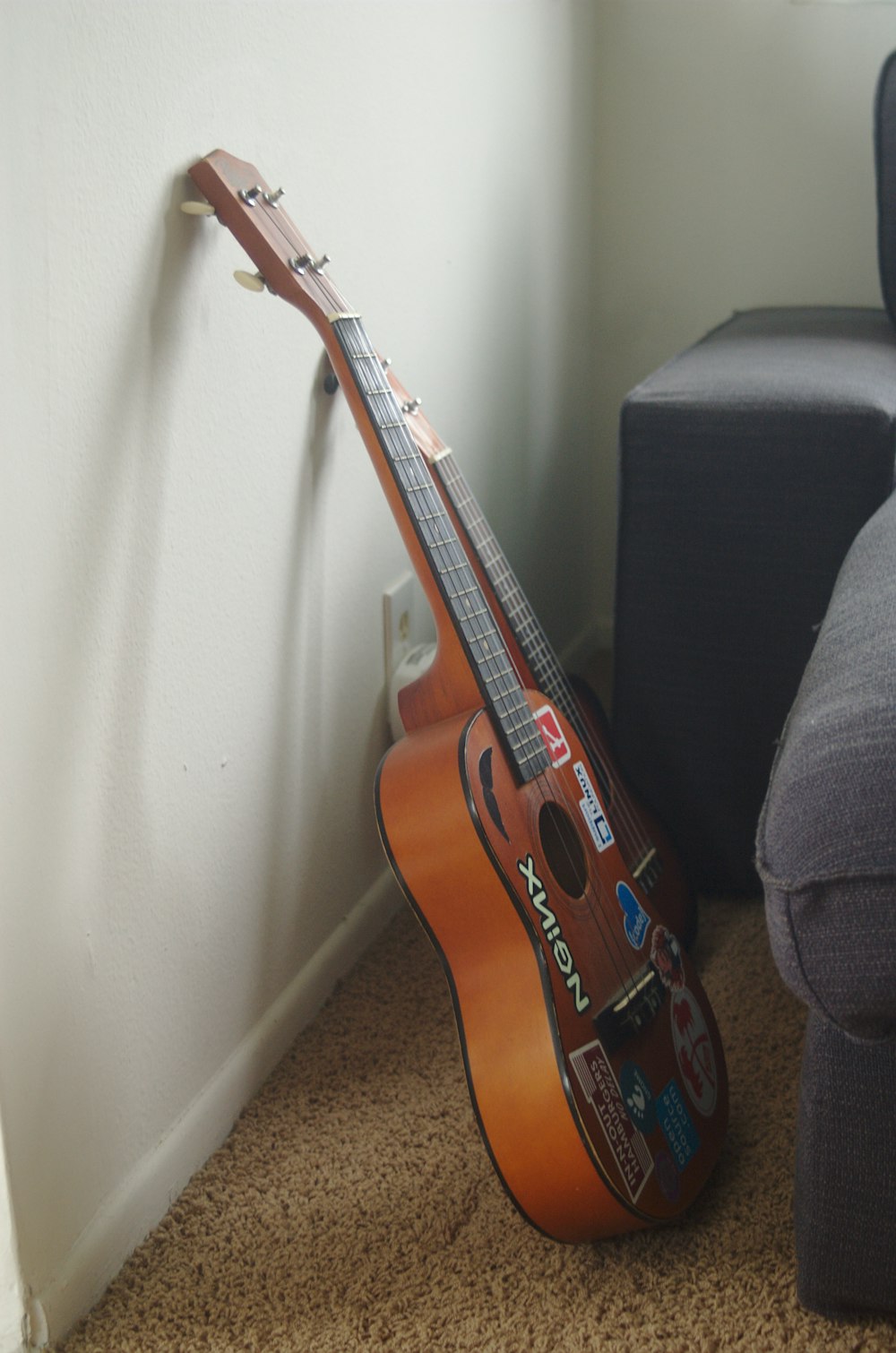 brown acoustic guitar leaned on white wall