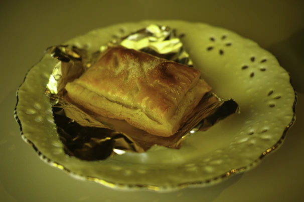 Close-up of a delicate pastry on a white plate with subtle golden hues.