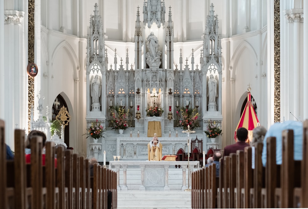 priest standing beside altar in front of sitting people