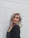 woman wearing black top standing beside white wall