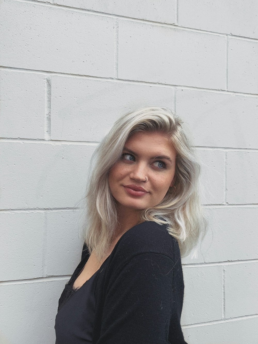 woman wearing black top standing beside white wall