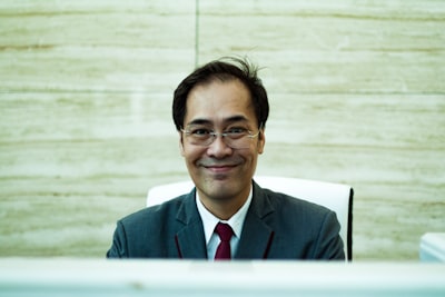 man wearing formal suit sitting and smiling qatar teams background