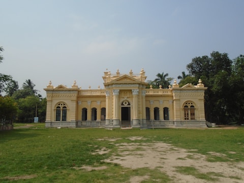 A sunlit colonial-era building with intricate balconies wrapped in lush greenery.