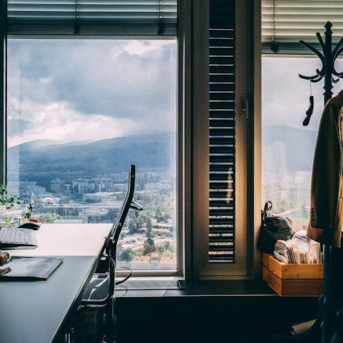 brown coat on hanger stand near window