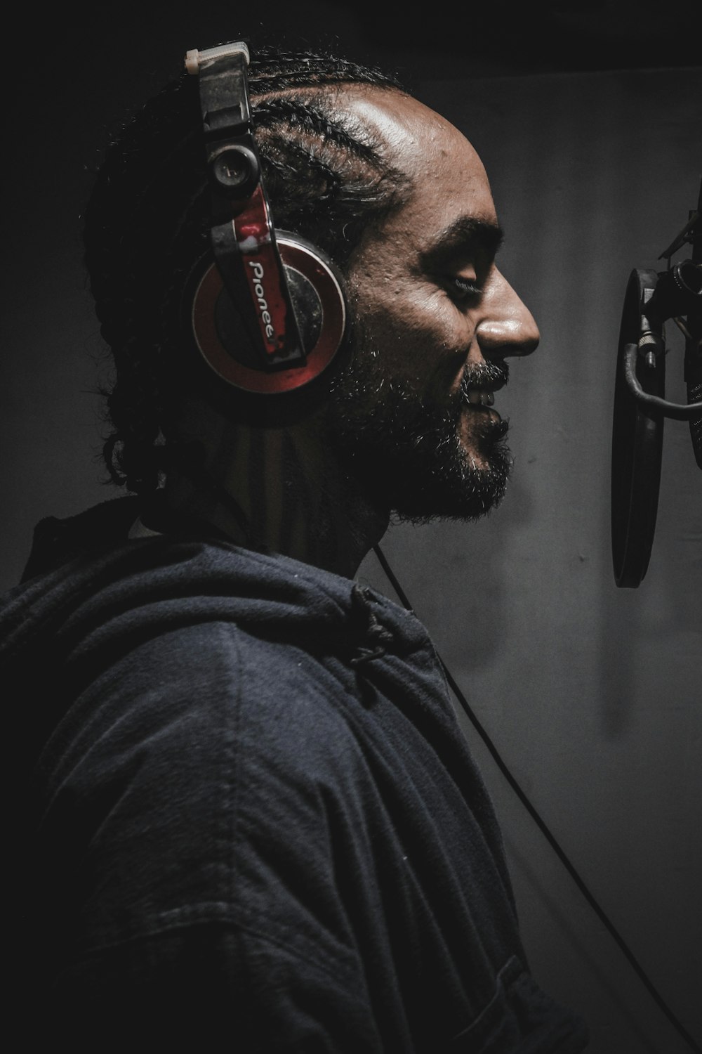 man wearing Pioneer corded headphones in front of pop filter