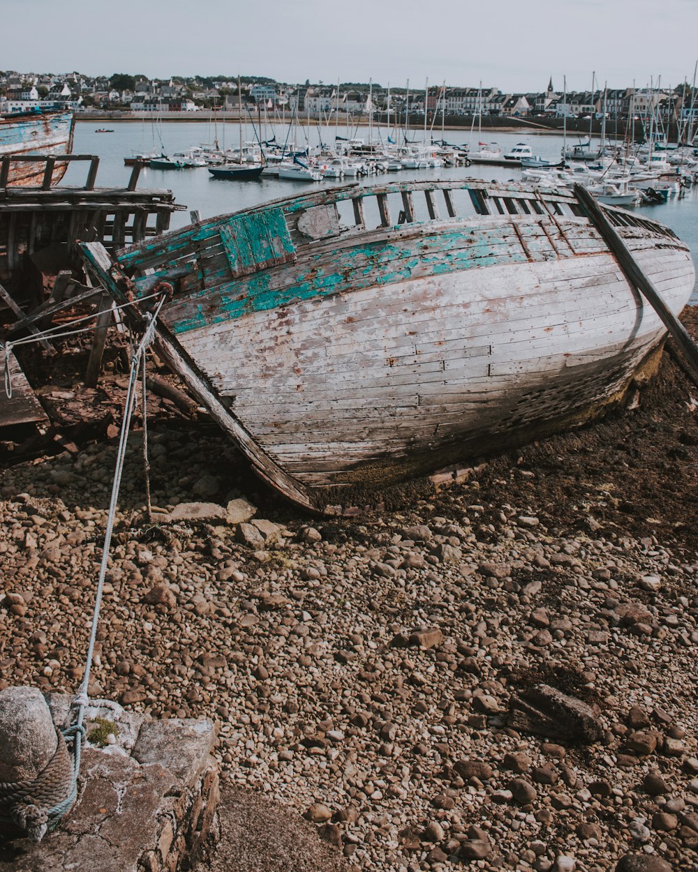 white and green dilapidated wooden boat on shore