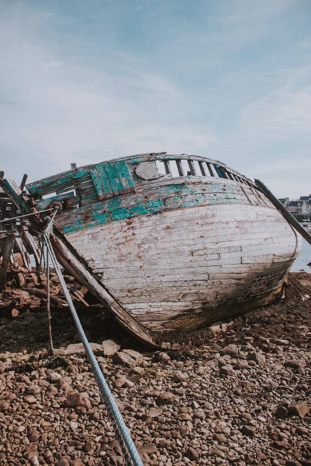 teal and white wrecked ship on shore during daytime