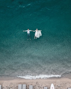 man and woman floating on blue beach