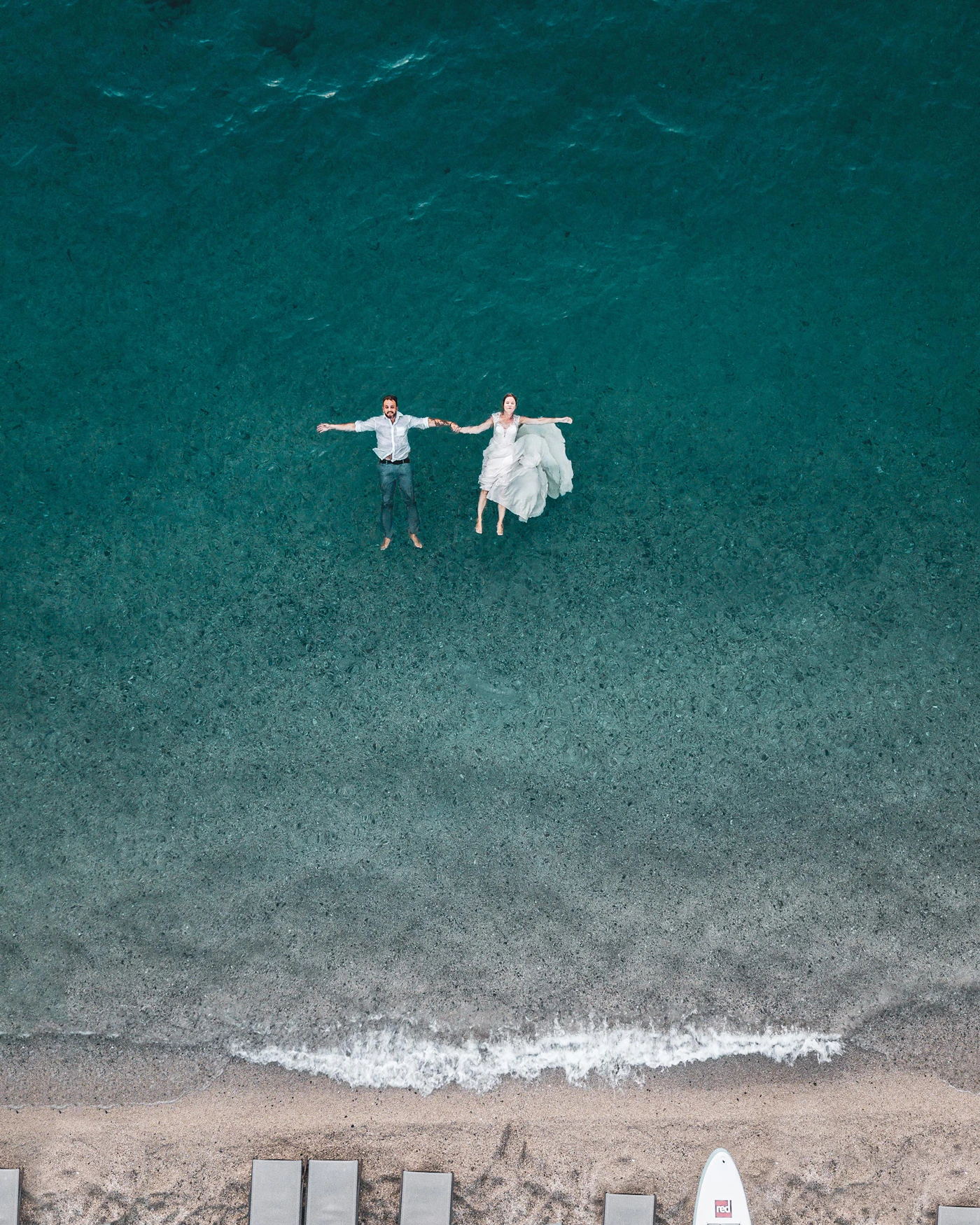 Newlywed couple floating together in clear blue tropical water