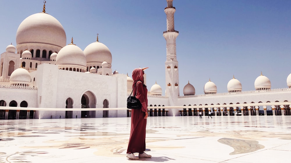 woman in red dress walking near mosque