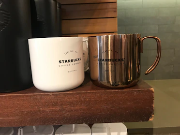 A sleek display of rare limited-edition Starbucks mugs with intricate designs under soft lighting.