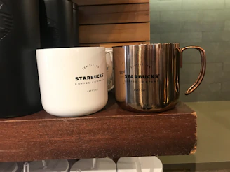 Cute Starbucks-themed mugs arranged on a light wooden shelf with soft natural light