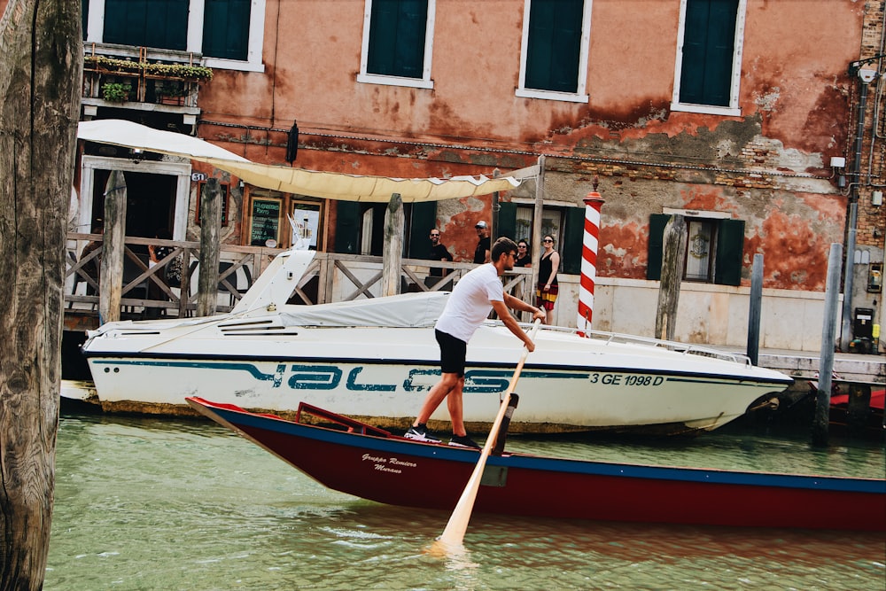 man paddling boat in water canal at daytime