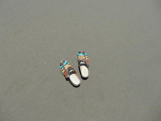 Brightly colored sandals arranged on a sandy beach background.