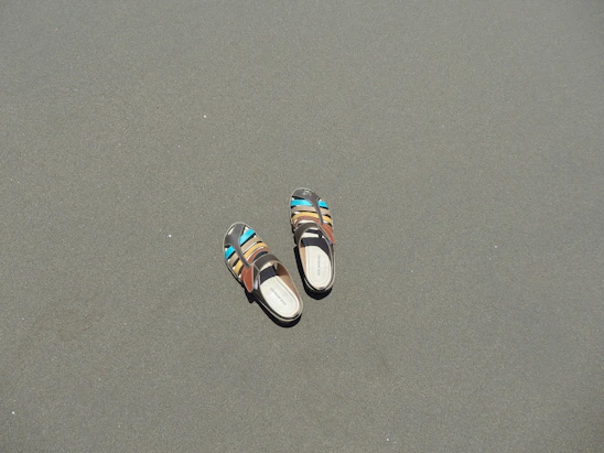 Close-up of a pair of colorful, handcrafted sandals resting on a sunlit wooden deck.