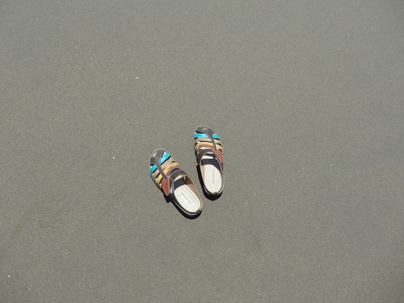 Close-up of a pair of colorful, handcrafted sandals resting on a sunlit wooden deck.