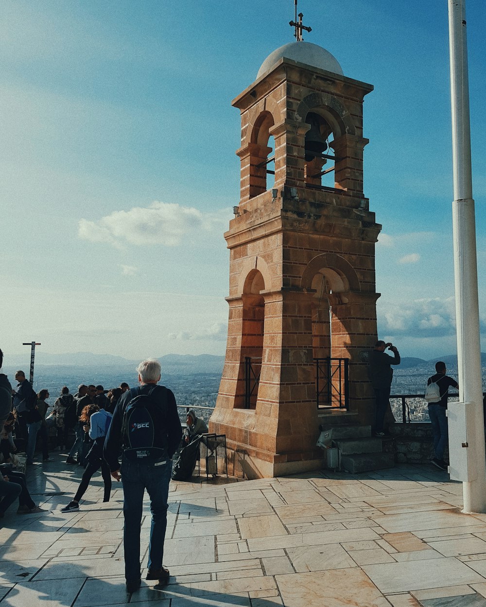 man carrying backpack near tower bell