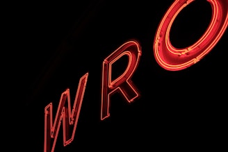 Neon red letters forming the partial word 'WRO' against a dark background, creating a glowing effect.