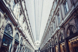 Modern shopping arcade interior with stylish storefronts and natural lighting.